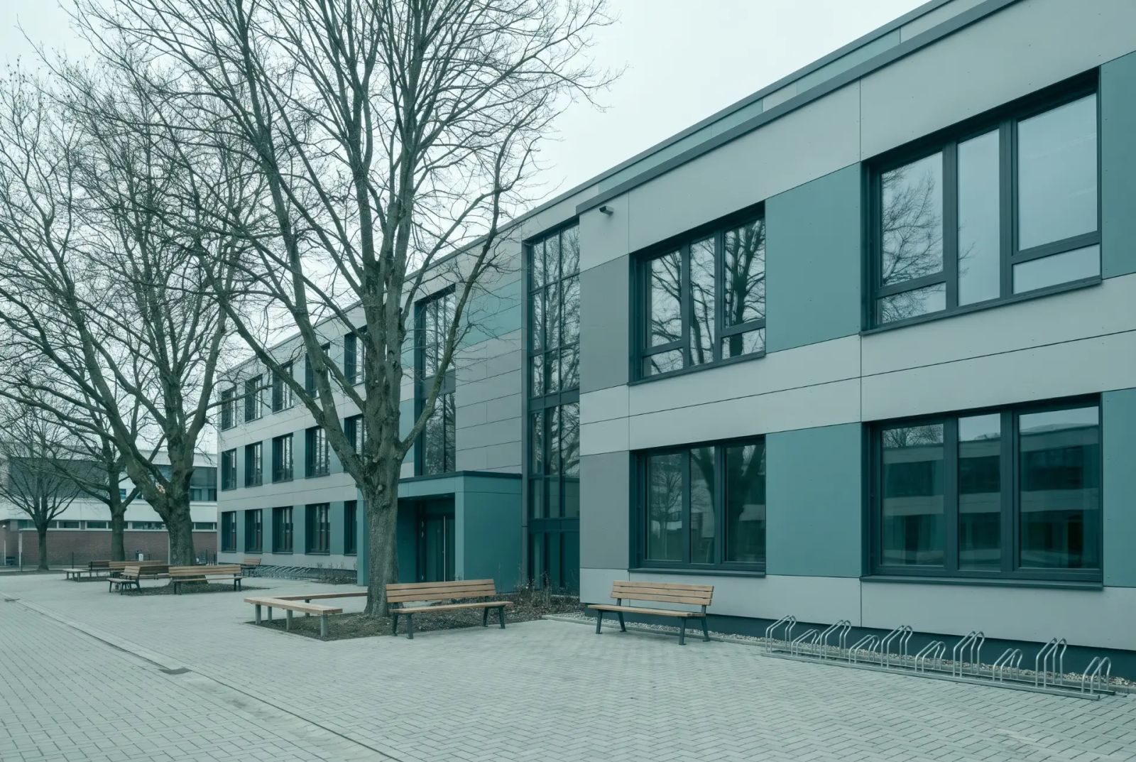 Modernes Schulgebäude mit Vorplatz und Bäumen